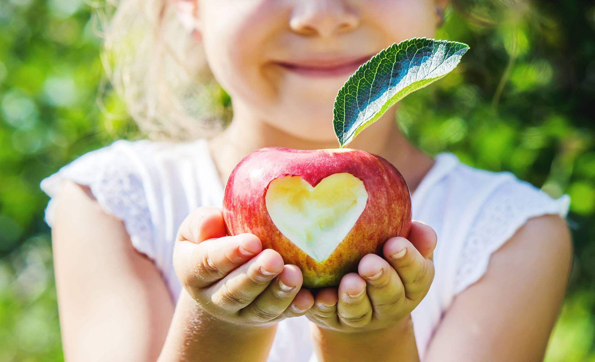 Girl holding apple with a cutout of a heart